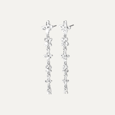 A pair of silver dangle earrings with a textured, organic chain design and small floral details, shown against a light off-white background.