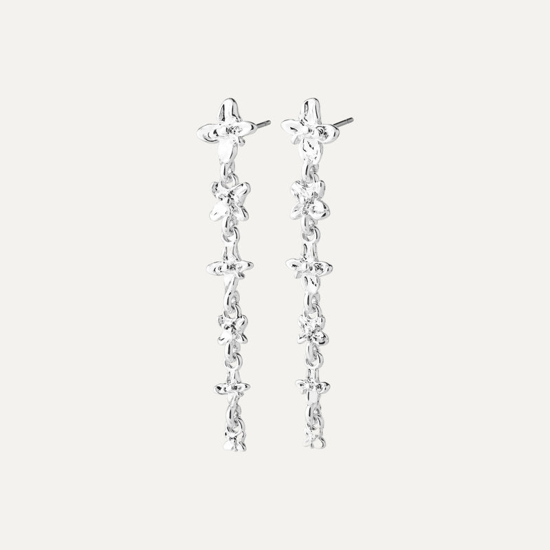 A pair of silver dangle earrings with a textured, organic chain design and small floral details, shown against a light off-white background.