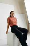 a_woman_wearing_rust_t-shirt_with_small_white_embroidered_logo_from_almost_summer