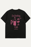 A black short-sleeve t-shirt with a pink graphic print on the back. The graphic features the text 'Do Nothing Club' surrounding illustrations of a wine bottle, a wine glass, grapes, and a hand holding a glass.
